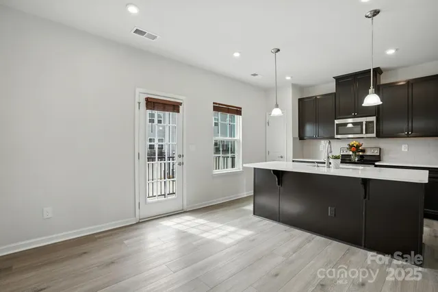 a view of a living room and kitchen with furniture wooden floor and windows