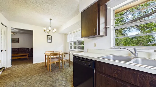 a kitchen with a sink a counter top space and living room view