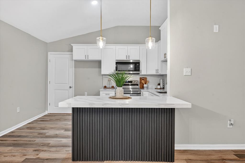 538 Pemberton Hill Road Dallas, TX 75217 - Photo 4 of 31 Kitchen island with a white marble-finish countertop and fluted dark wood paneling