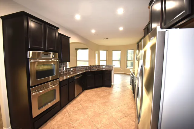 a kitchen with granite countertop a refrigerator and a stove top oven