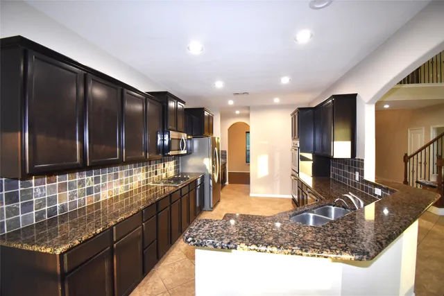 a large kitchen with kitchen island granite countertop a large counter top and stainless steel appliances