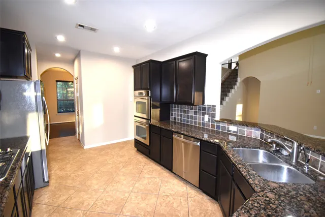 a large kitchen with kitchen island granite countertop a sink and a stove top oven with wooden floor