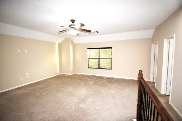 an empty room with windows and ceiling fan
