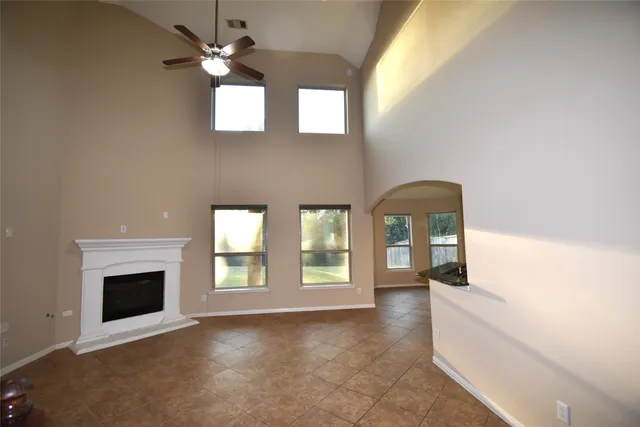 a view of an empty room with chandelier fan and fire place