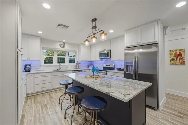 a kitchen with stainless steel appliances granite countertop a stove a refrigerator and a sink