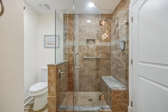 a bathroom with a granite countertop sink a toilet and shower