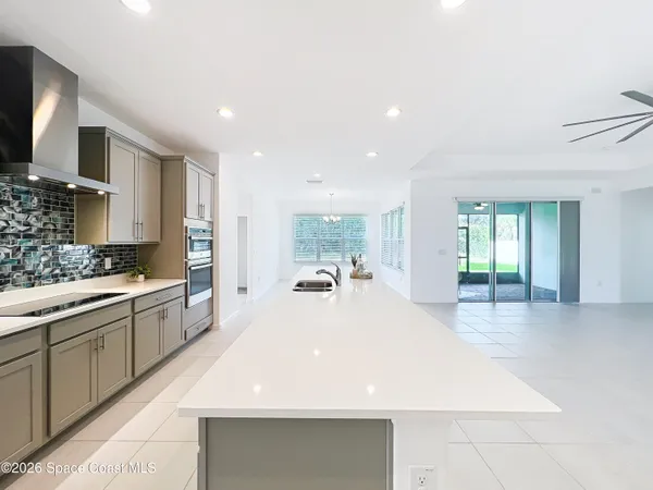 a large white kitchen with kitchen island a sink stainless steel appliances and cabinets