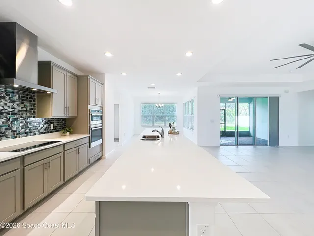 a large white kitchen with kitchen island a sink stainless steel appliances and cabinets