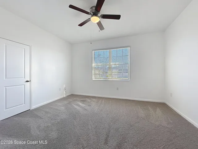 an empty room with ceiling fan and windows