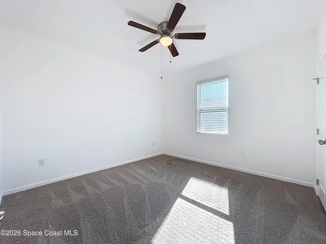 an empty room with a window and a fan