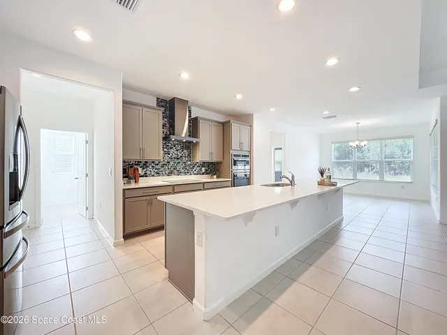 a large white kitchen with a refrigerator a counter top space and cabinets