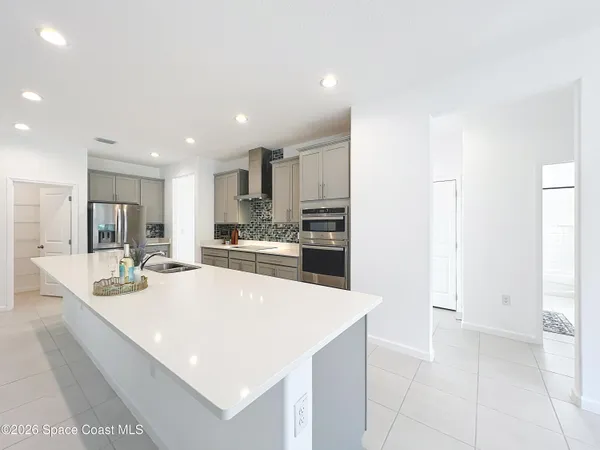 a large white kitchen with a refrigerator a stove a sink and a counter top space