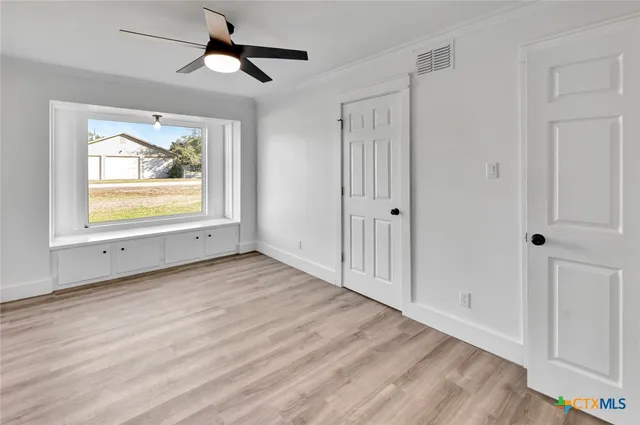 a view of an empty room with window and wooden floor