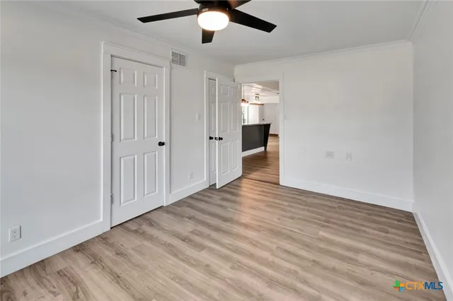 an empty room with wooden floor closet and windows
