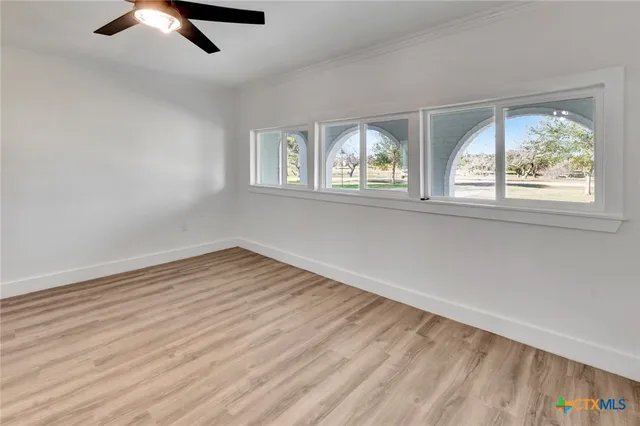 a view of empty room with wooden floor and fan