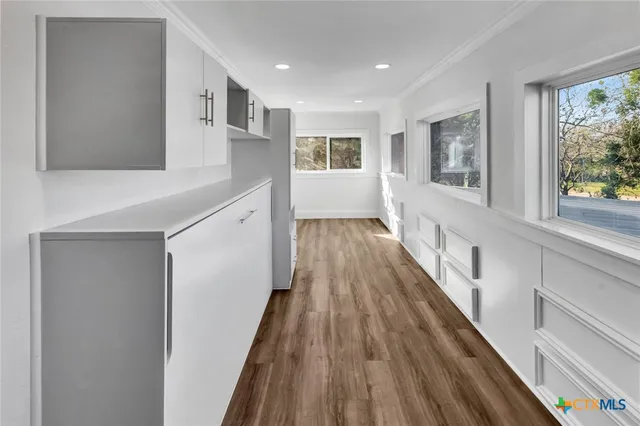a hallway with wooden floor and windows