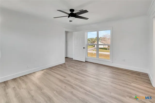 a view of empty room with wooden floor and fan