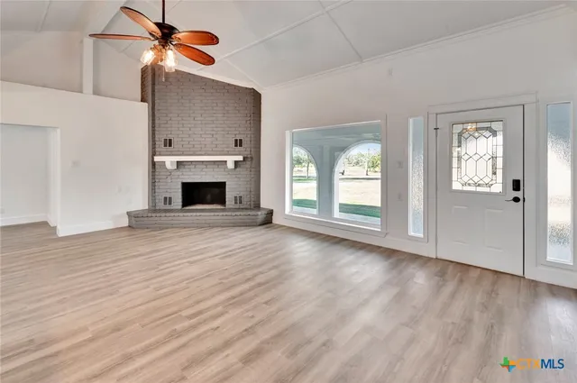 a view of an empty room with window and wooden floor