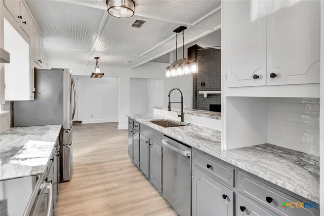 a kitchen with granite countertop a sink stainless steel appliances and cabinets
