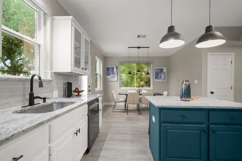 a kitchen with kitchen island granite countertop a sink a counter space appliances and cabinets