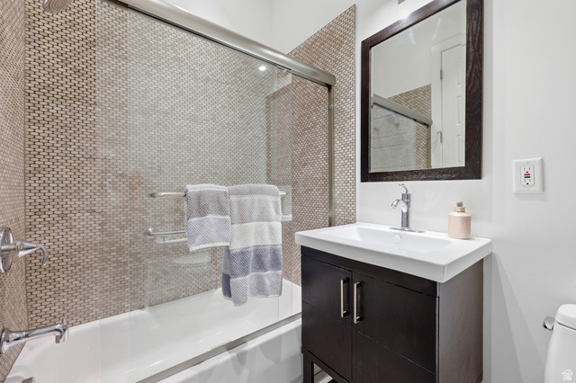 1389 Millbrook Way Bountiful, UT 84010 - Photo 42 of 74 Bathroom featuring a dark wood-finish vanity with an integrated white sink, a framed mirror, and a tiled shower-bath combination with a glass enclosure