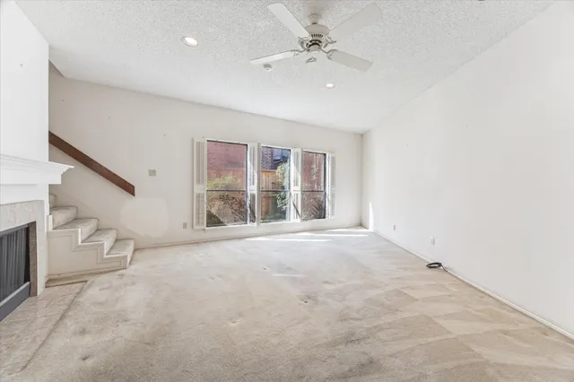 an empty room with windows and ceiling fan