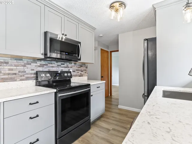 a kitchen with stainless steel appliances granite countertop a refrigerator a sink and a stove