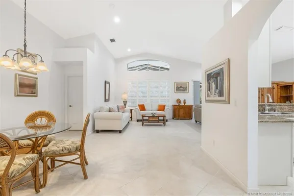 a large white kitchen with granite countertop a stove top oven a sink a dining table and chairs