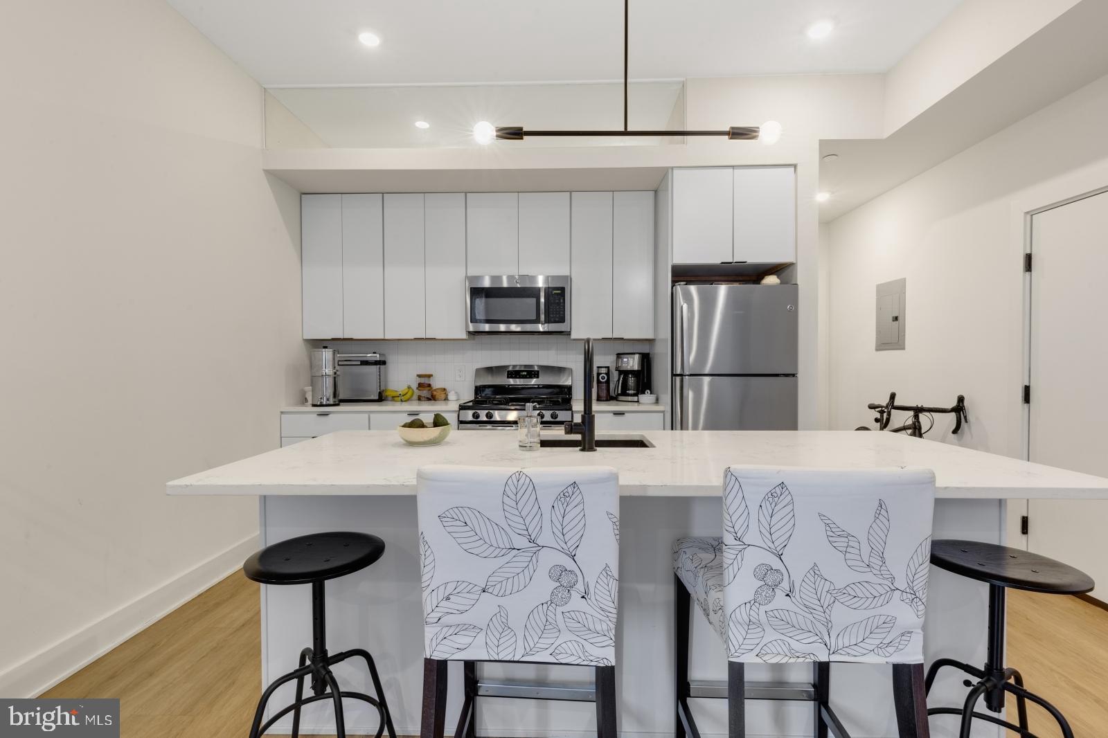 630 Federal Street, Unit 304 Philadelphia, PA 19147 - Photo 5 of 26 a kitchen with kitchen island a stove a table and chairs