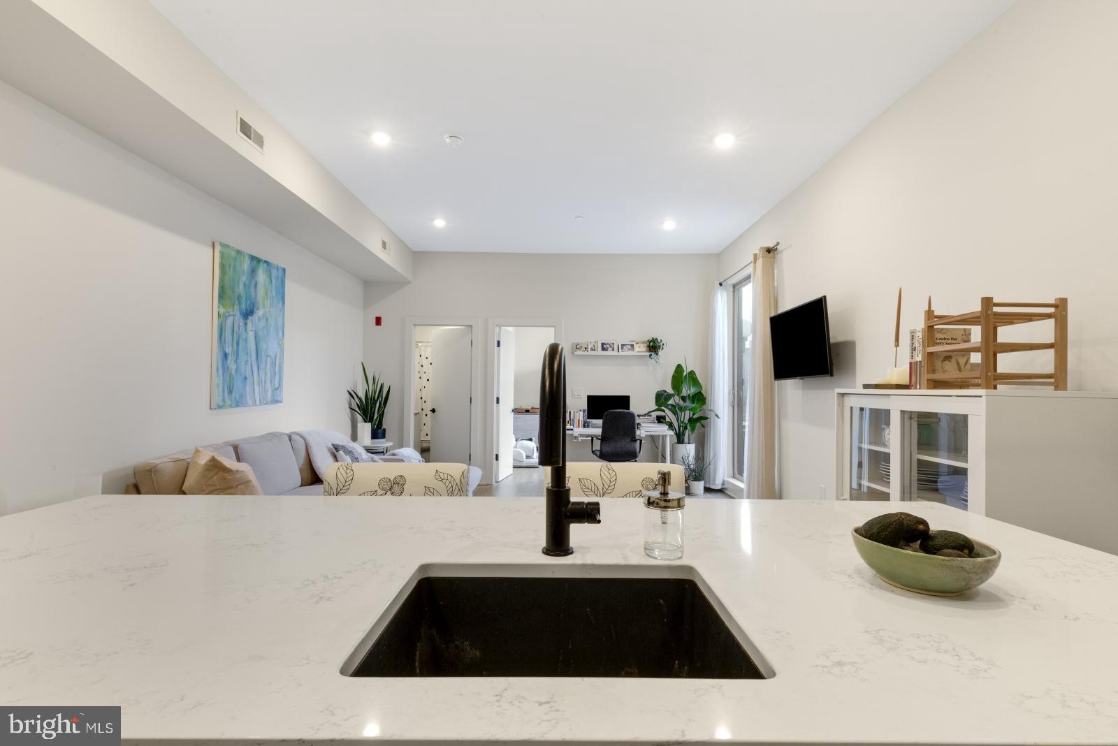 630 Federal Street, Unit 304 Philadelphia, PA 19147 - Photo 6 of 26 a kitchen with stainless steel appliances a sink a flat screen tv and couches