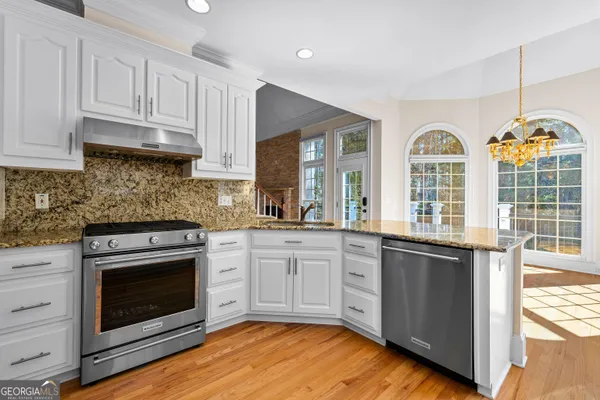 a kitchen with granite countertop white cabinets stainless steel appliances and a sink