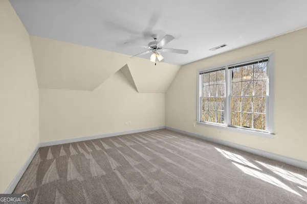 an empty room with chandelier fan and windows