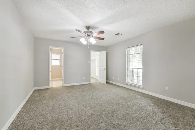 an empty room with windows and chandelier fan