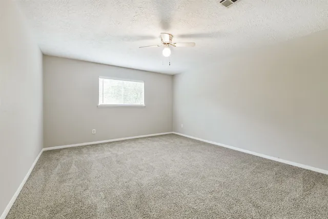 an empty room with a ceiling fan and a window