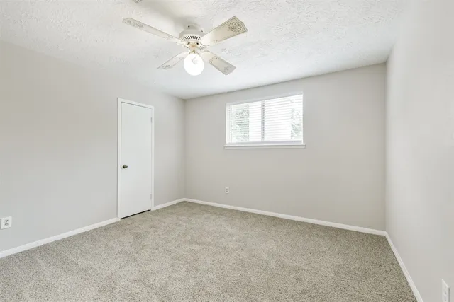 an empty room with a chandelier fan and windows