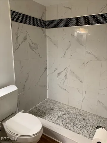 a white toilet sitting next to a shower