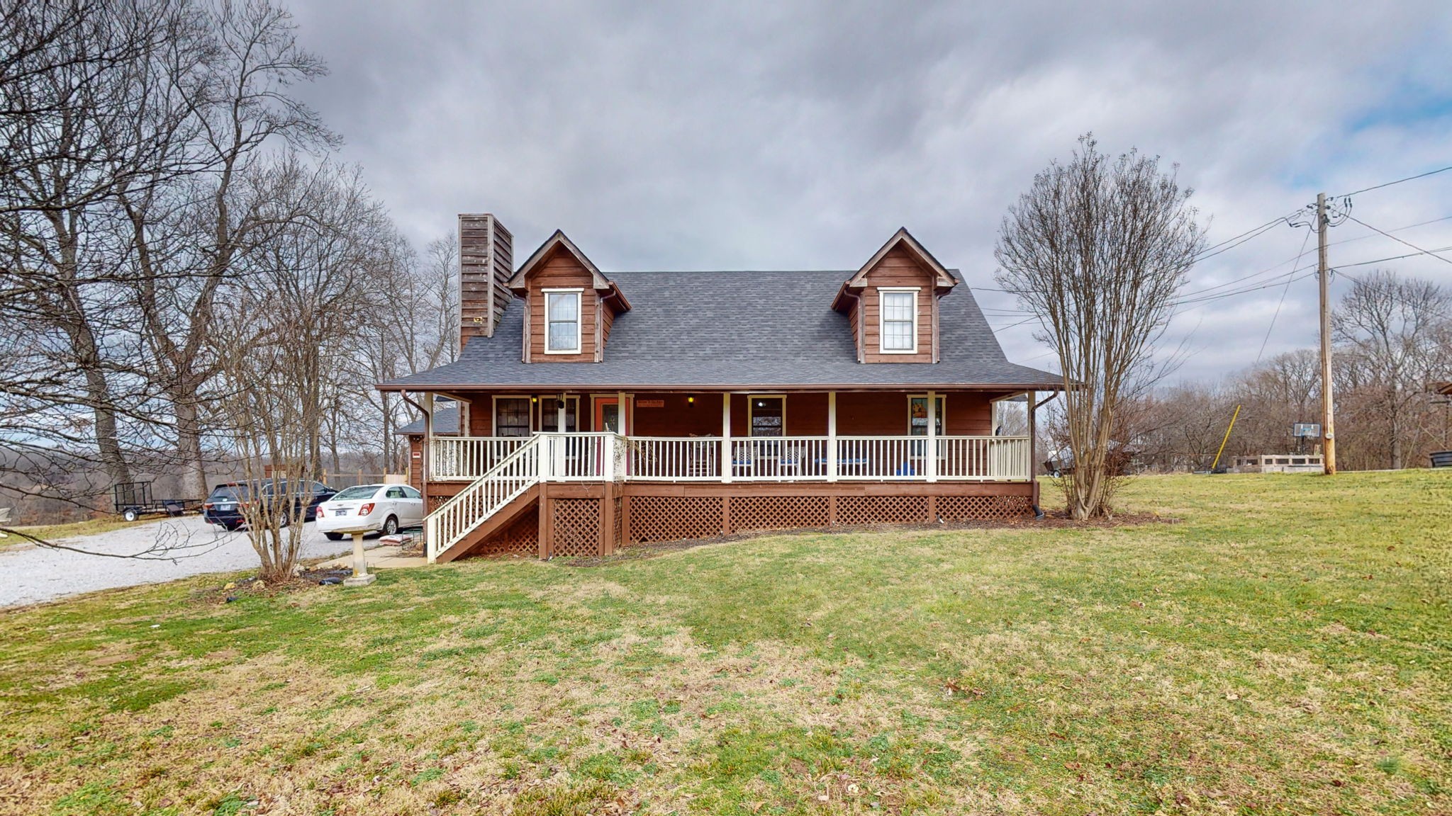 a front view of a house with a yard and large tree