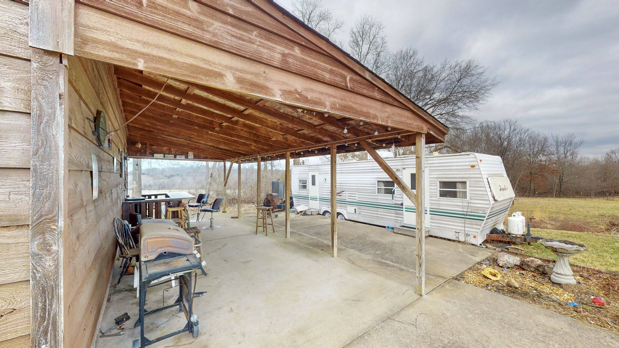 2459 Toler Road Woodlawn, TN 37191 - Photo 29 of 48 a view of a patio with table and chairs under an umbrella with a barbeque