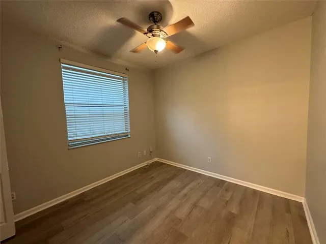 an empty room with a chandelier fan and windows