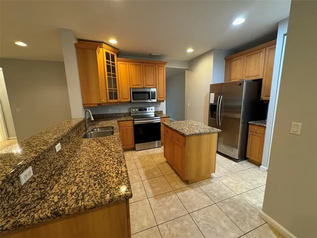 a kitchen with stainless steel appliances granite countertop a refrigerator a stove a sink and a microwave