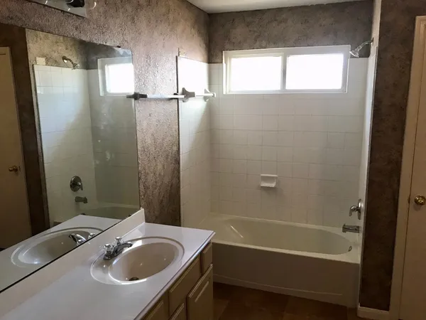 a bathroom with a tub a sink a window and a shower