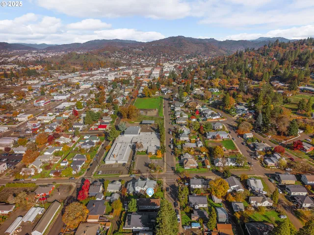 an aerial view of residential house with parking and city view