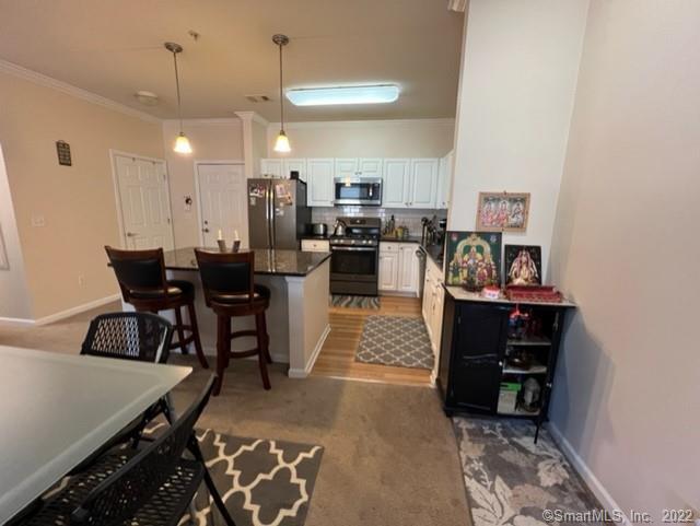 25 Adams Avenue, Unit 301 Stamford, CT 06902 - Photo 12 of 26 a kitchen with stainless steel appliances kitchen island granite countertop dining table chairs and a refrigerator
