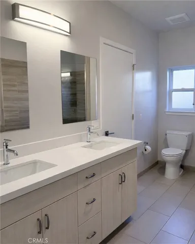 a bathroom with a double vanity sink mirror and toilet
