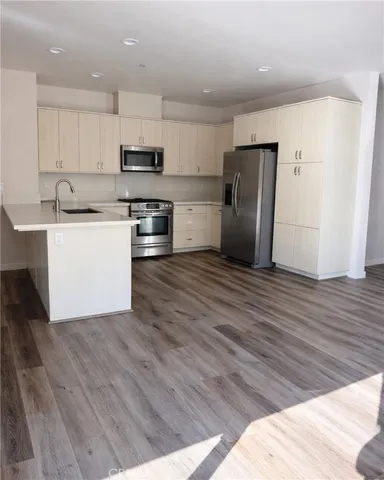 a kitchen with stainless steel appliances granite countertop a refrigerator a sink dishwasher a stove and white countertops with wooden floor