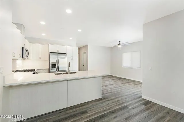 a kitchen with stainless steel appliances granite countertop a sink a stove and white cabinets with wooden floor