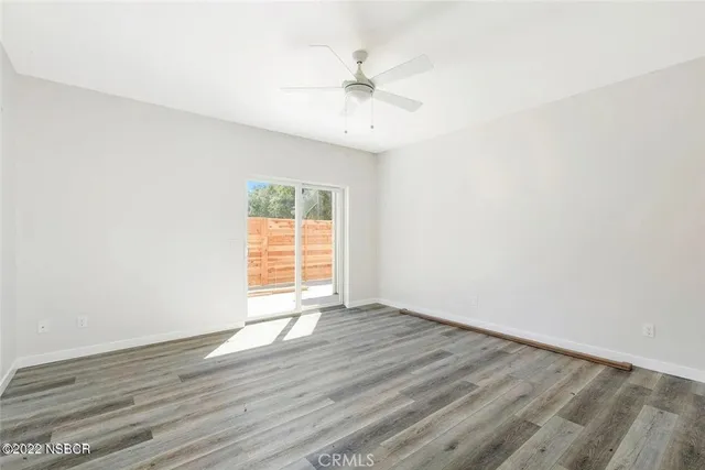 an empty room with wooden floor fan and windows