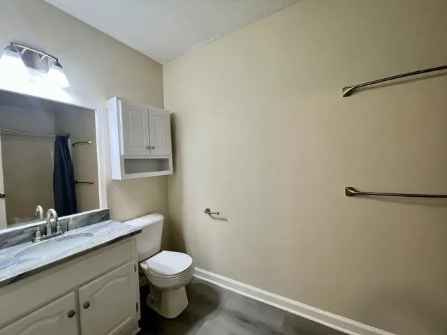 a bathroom with a granite countertop sink toilet and a mirror