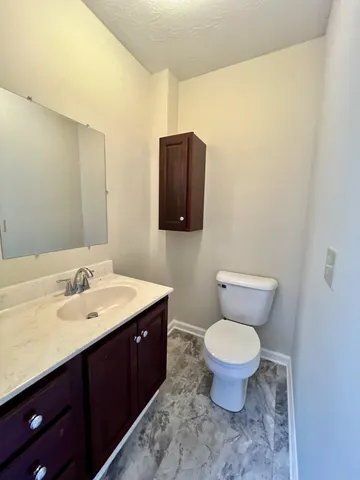 a bathroom with a granite countertop toilet sink and mirror
