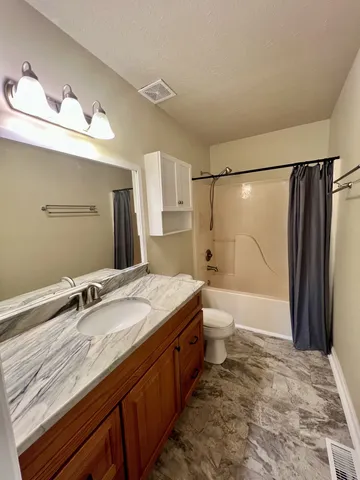 a bathroom with a granite countertop sink a toilet and shower
